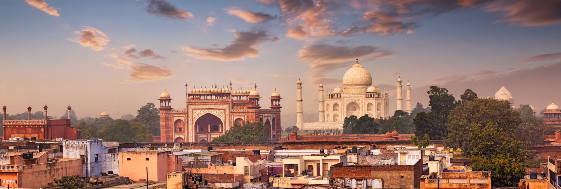 Taj Mahal and Agra skyline at sunset, seen from across the rooftops