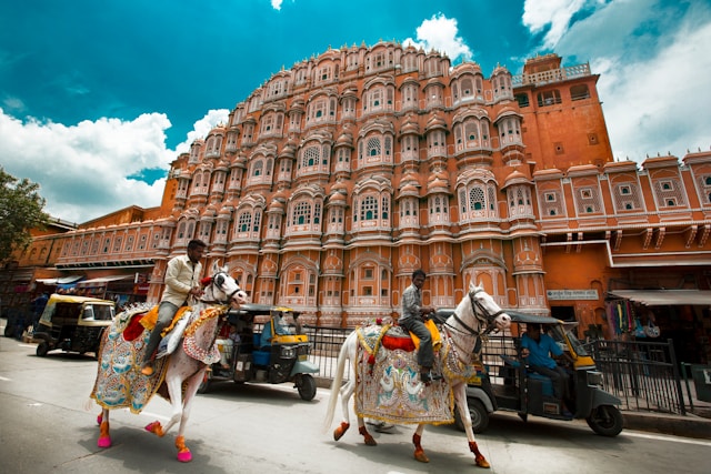 Hawa Mahal facade with decorated horses passing on the street, Jaipur